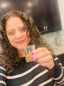 Photo of lady holding up a shot glass of Glow liquid collagen