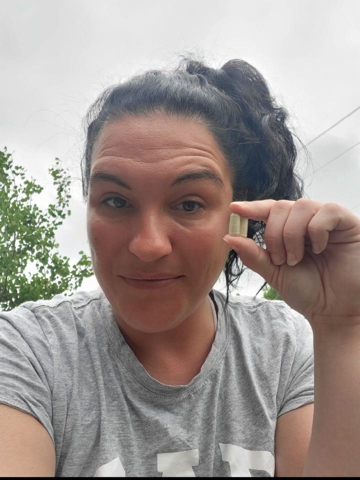 Photo of lady holding up 2 capsule of Enrich digestive enzymes