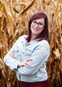 photo of a women standing in front of corn stalks