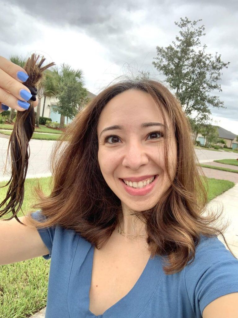 a lady holding up 6 inches of hair that she just cutoff