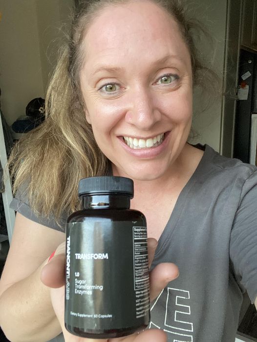 woman smiling holding a bottle of Transform