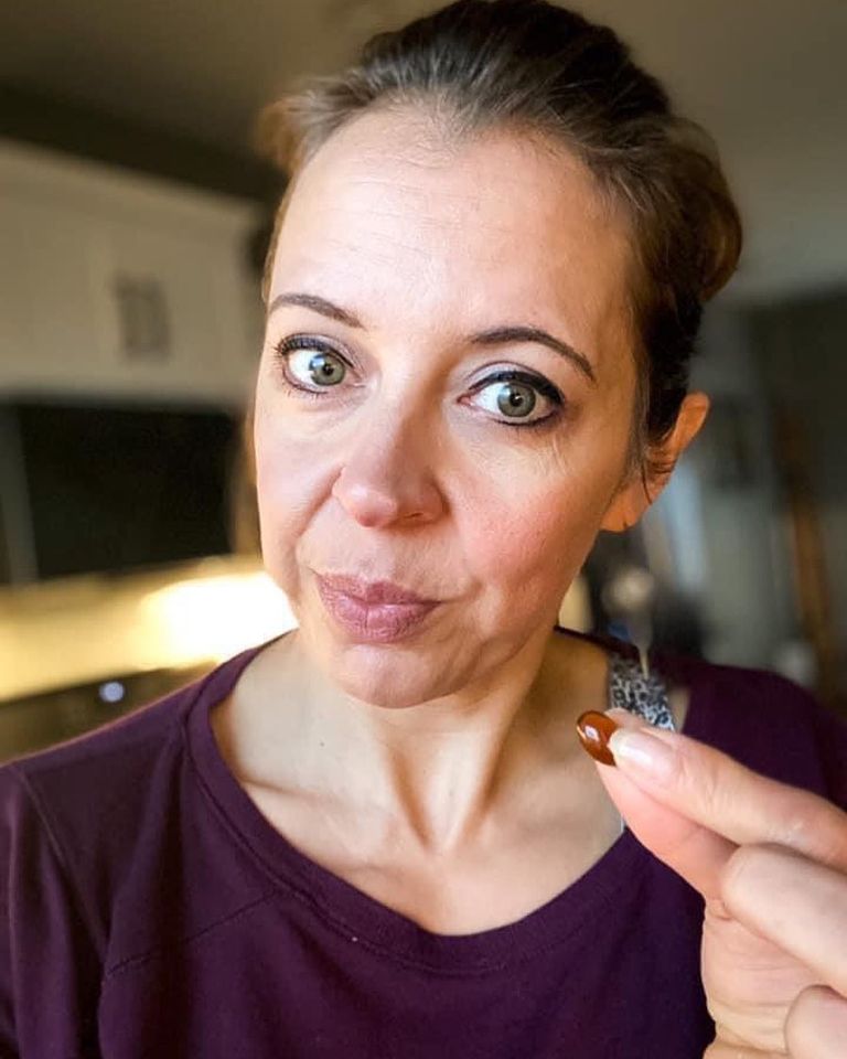 A woman holding up a Renew pill