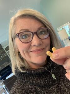 A very happy woman holding up two capsules of Optimize